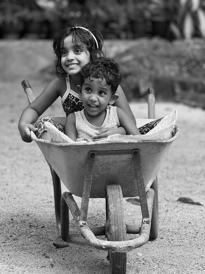The Art of Drawing Readers In: Your attractive post title goes here Black and white photo of two smiling children having fun in a wheelbarrow outside.